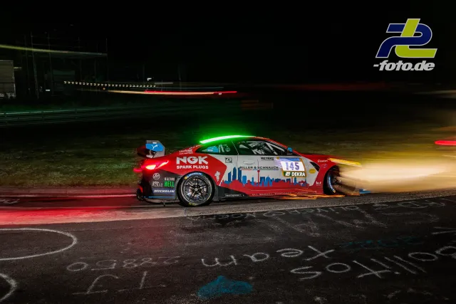 Hyundai i30 N TCR Nummer 145 bei Nachtfahrt auf dem Nürburgring während des 24-Stunden-Rennens, vorbeifahrendes Auto im Hintergrund.