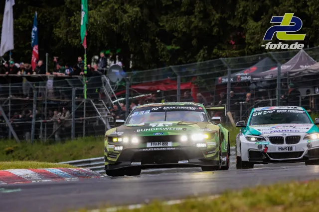 Ein Ford Mustang mit Bundeswehr-Lackierung und ein BMW auf der Nordschleife während des 24h-Rennens bei dichtem Verkehr.
