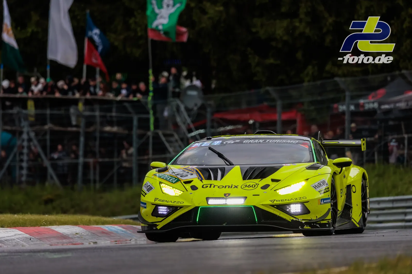 Neongelber Lamborghini Huracan GT3 EVO2 #786 in Kurve auf dem Nürburgring beim 24h-Rennen, Zuschauer im Hintergrund