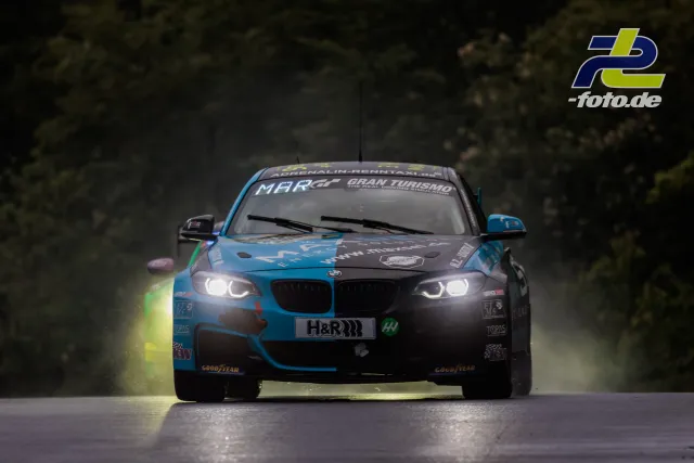 BMW Rennwagen frontal auf nasser Strecke beim Qualifying zum 24h-Rennen am Nürburgring, Scheinwerfer eingeschaltet.
