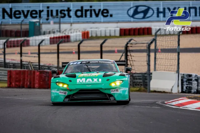 Türkiser Aston Martin GT-Rennwagen frontal auf dem Nürburgring, im Hintergrund Streckenbegrenzung und Hyundai-Werbebande