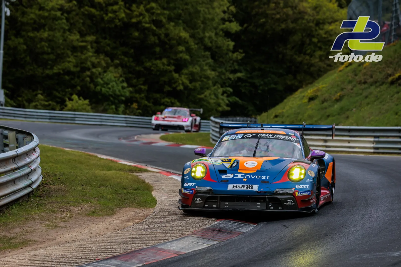 Porsche 911 GT3 R in blau-orange mit Startnummer 4 auf der Nordschleife, im Hintergrund ein weiteres GT3-Fahrzeug