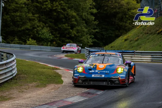 Porsche 911 GT3 R in blau-orange mit Startnummer 4 auf der Nordschleife, im Hintergrund ein weiteres GT3-Fahrzeug