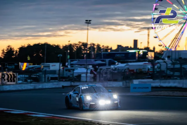 Porsche 911 GT3 R mit Startnummer 054 in der Abenddämmerung auf der Nordschleife während des 24-Stunden-Rennens am Nürburgring.