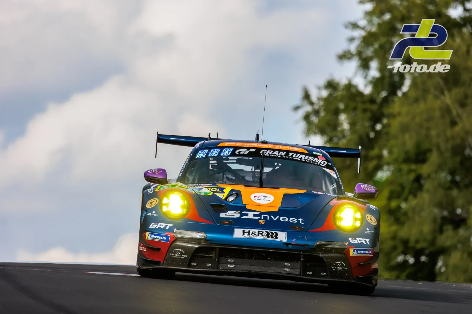 Porsche 911 GT3 R in dunkelblaue-orange Lackierung mit H&R-Branding im Rennen auf der Nordschleife des Nürburgrings.