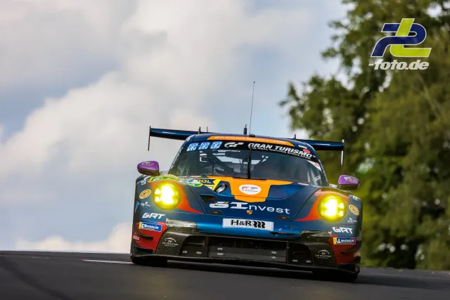 Porsche 911 GT3 R in dunkelblaue-orange Lackierung mit H&R-Branding im Rennen auf der Nordschleife des Nürburgrings.