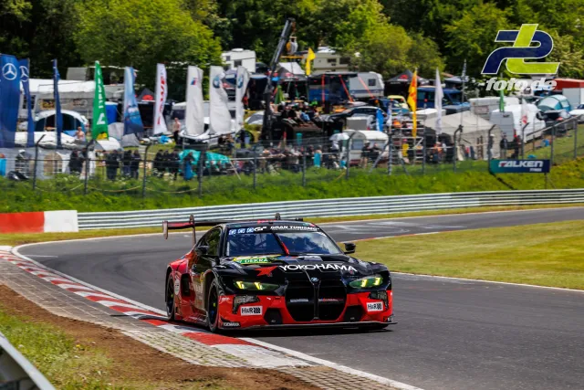 BMW M4 GT3 in schwarz-rot mit Yokohama-Sponsoring auf der Nordschleife am Nürburgring, Fahrerperspektive vor Boxengasse.