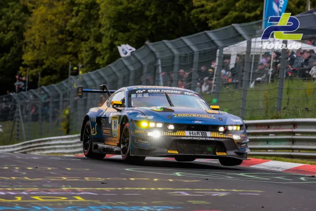 Ford Mustang SP9 des HAUPT RACING TEAM in Kurve auf der Nordschleife beim 24h-Rennen Nürburgring, Zuschauertribüne im Hintergrund.
