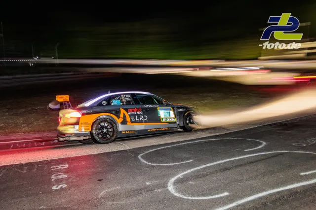 Rennwagen in der Kurve bei Nachtrennen am Nürburgring mit dramatischer Bewegungsunschärfe und glühender Bremse