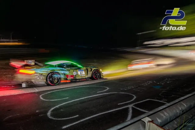 Porsche mit Startnummer 67 im nächtlichen Rennen auf dem Nürburgring, Mitzieher mit Bewegungsunschärfe und leuchtenden Rücklichtern.