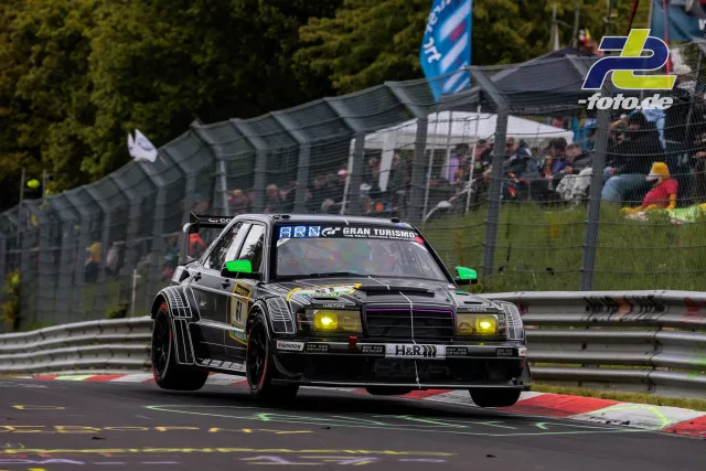 HWA EVO.R mit gelben Scheinwerfern im Renneinsatz auf der Nürburgring-Nordschleife mit Zuschauertribüne