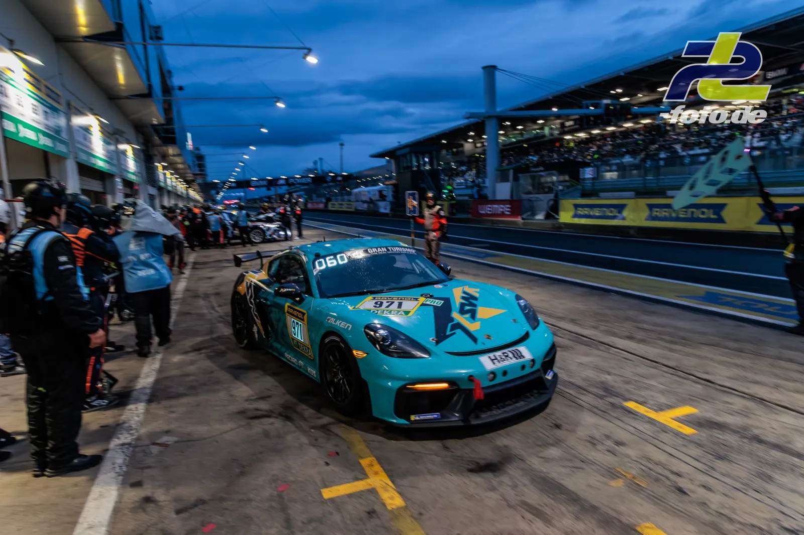 Porsche 718 Cayman GT4 Clubsport verlässt die Box während des 24h-Rennens auf dem Nürburgring in der Dämmerung.