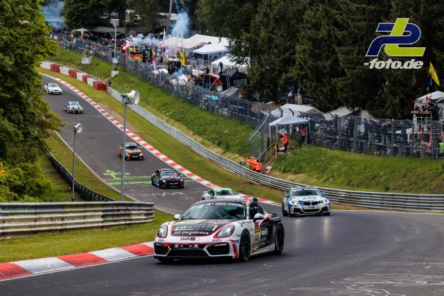 Mehrere Rennfahrzeuge auf der Nordschleife des Nürburgrings während des 24-Stunden-Rennens, Zuschauer an der Strecke.