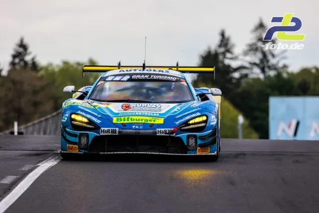 McLaren 720S GT3 in blau-weißer Lackierung frontal auf dem Nürburgring während des 24h-Rennens, bewölkter Himmel.