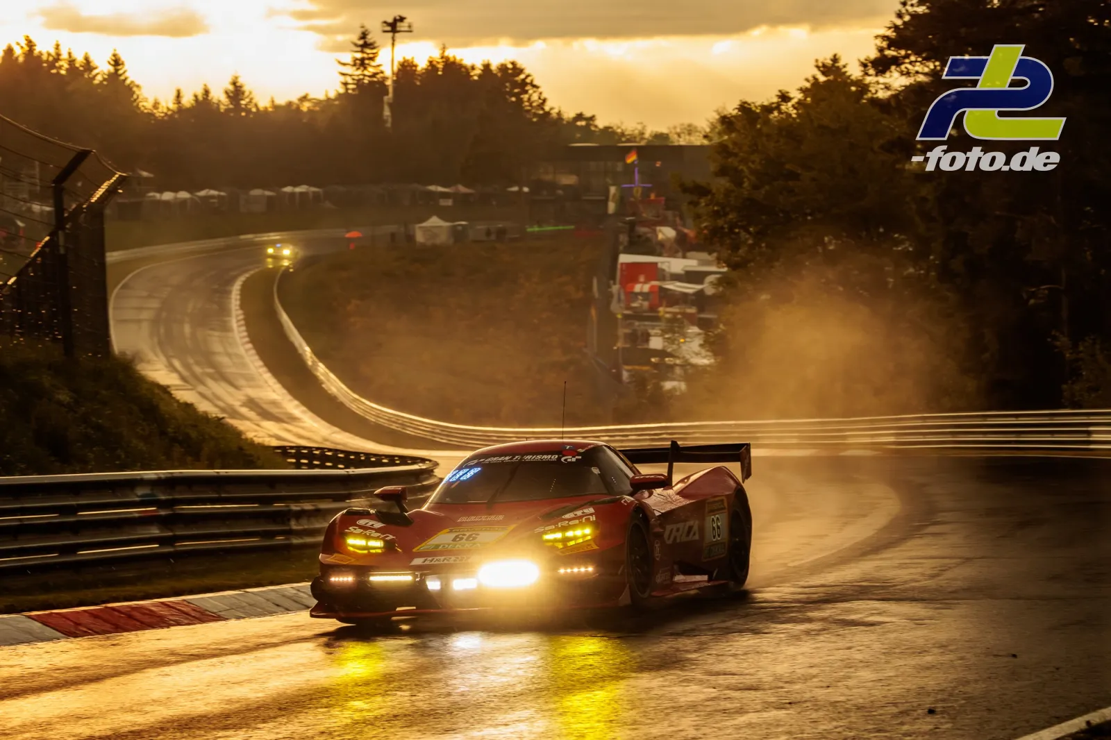Rennwagen durchfährt eine nasse Kurve auf der Nordschleife bei Gegenlicht und dramatischer Abendsonne.