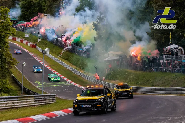 Formationsrunde beim 24h-Rennen am Nürburgring mit bunten Rauchfackeln der Zuschauer an der Strecke.
