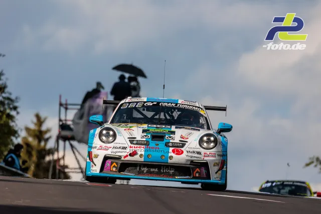 Porsche 911 GT3 R in weiß-blauer Lackierung springt über die Kuppe am Nürburgring während des 24h-Rennens