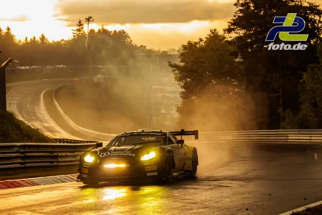GT3-Rennwagen fährt im Gegenlicht durch Kurve auf dem Nürburgring bei dramatischen Lichtverhältnissen.