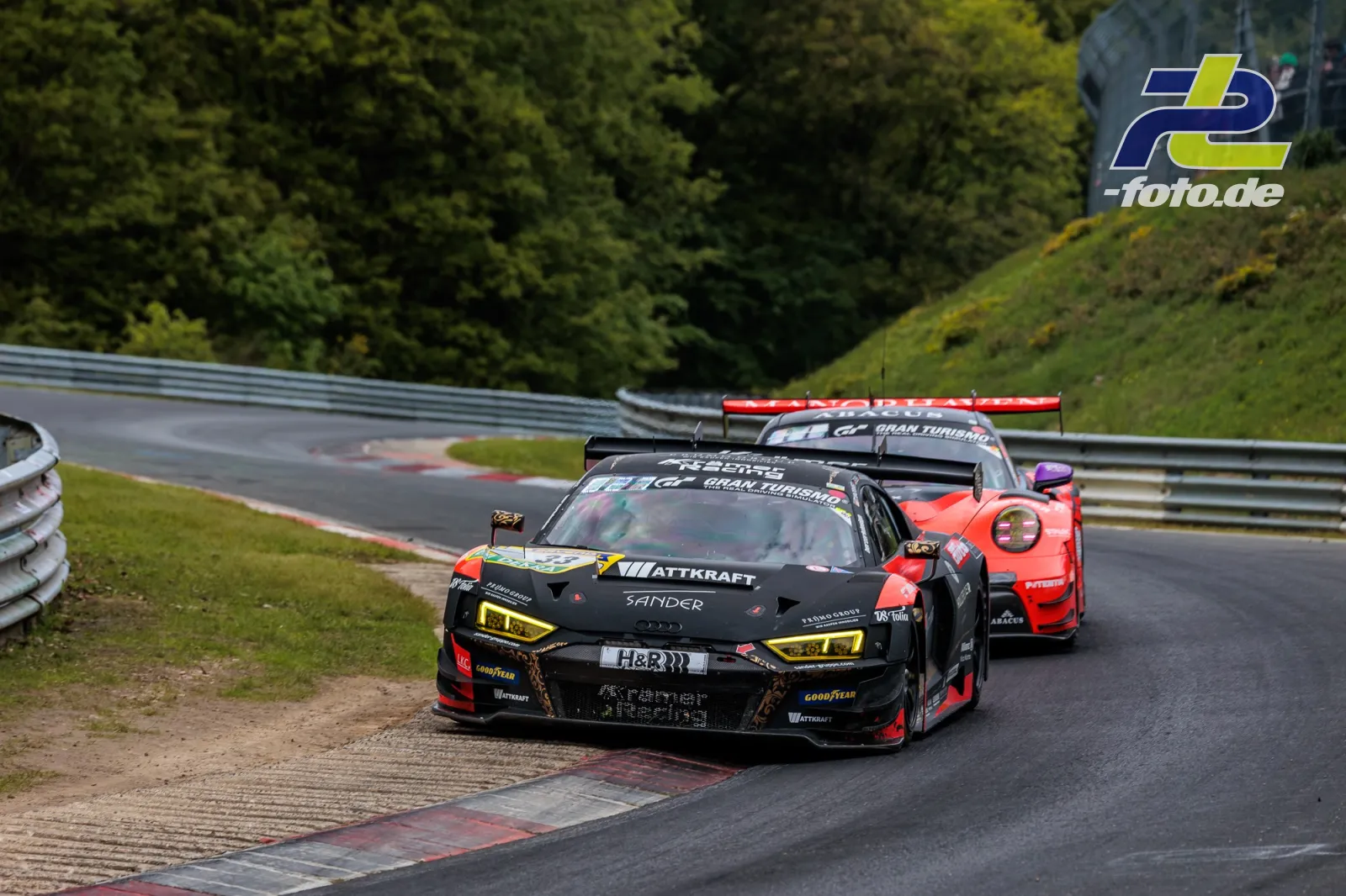 Zwei GT3-Rennwagen in der Kurve auf der Nordschleife während des 24h-Rennens. Im Vordergrund ein Audi R8, dahinter ein Porsche 911.