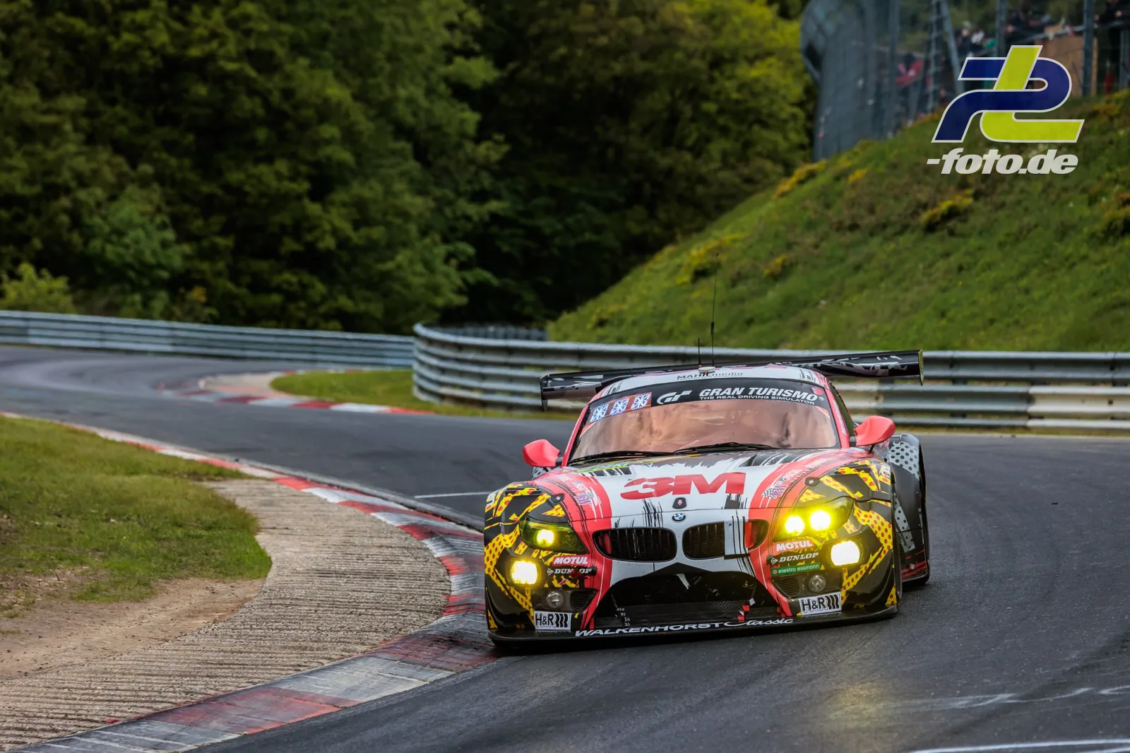 BMW Z4 GT3 auf dem Nürburgring während des 24-Stunden-Rennens in einer Kurve mit Randsteinen und Leitplanke.