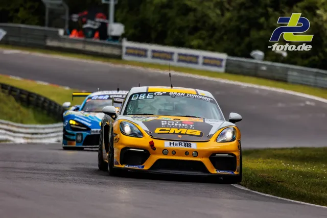 Porsche Cayman GT4 Clubsport in gelb-schwarz verfolgt von einem blauen GT3-Rennwagen während des Qualifyings zum 24h-Rennen auf dem Nürburgring.