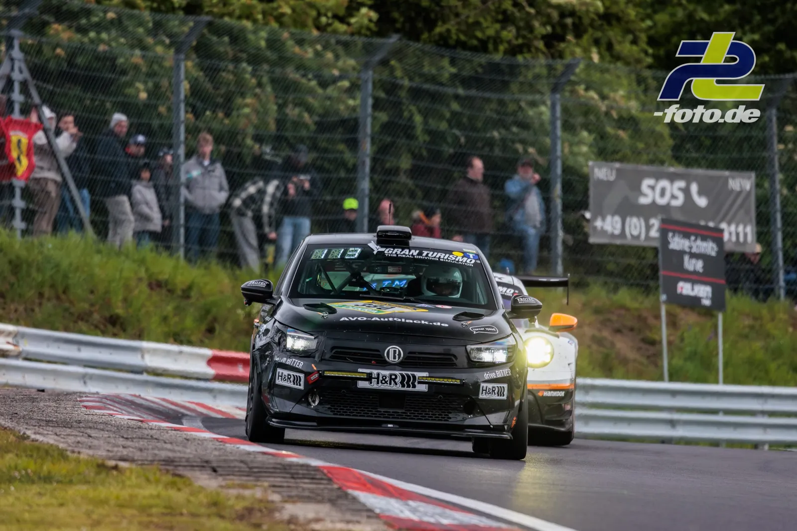 Opel Corsa GS Line 130* Nr. 380 im Zweikampf beim 24h-Rennen am Nürburgring, gefolgt von einem weiteren Fahrzeug, Zuschauer am Zaun.