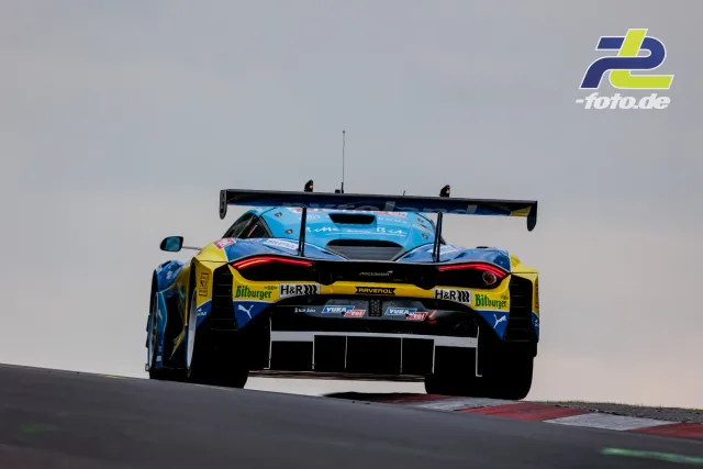 McLaren GT3 in hellblau-gelber Lackierung über der Kuppe am Nürburgring während des 24-Stunden-Rennens.