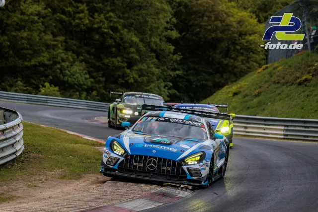 Mercedes-AMG GT3 in blau-weißer Lackierung führt Fahrzeuggruppe auf Nordschleife im Rennen, Schikane mit nasser Fahrbahn.