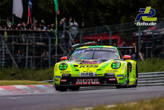 Porsche 911 GT3 R in auffälliger neongelb-grüner Lackierung während des 24h-Rennens auf dem Nürburgring mit Zuschauern im Hintergrund