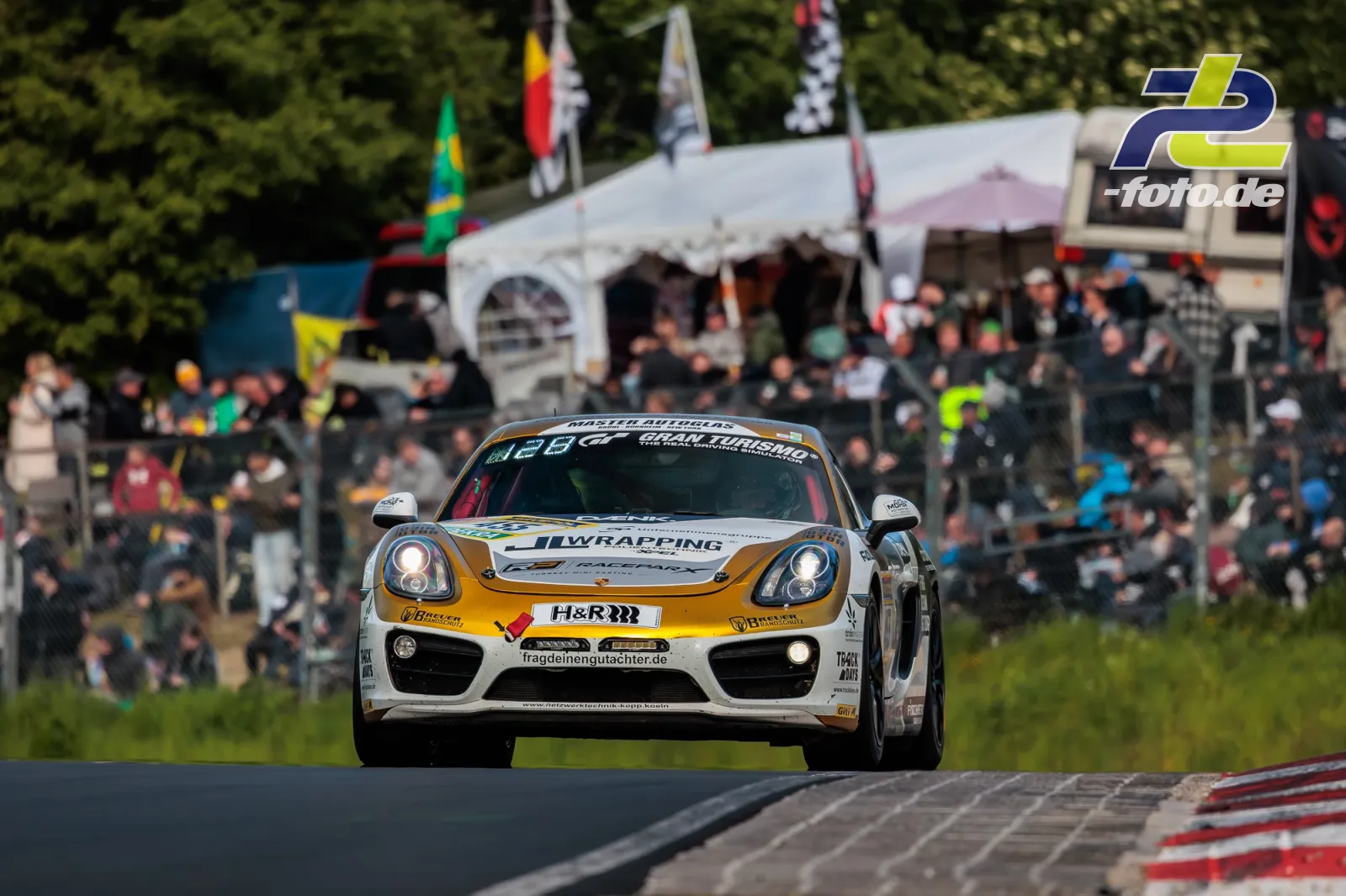 Porsche Cayman am Nürburgring mit Zuschauern im Hintergrund während des 24h-Rennens