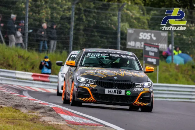 BMW Rennwagen in schwarz-oranger Lackierung auf der Nordschleife des Nürburgrings während des 24-Stunden-Rennens.