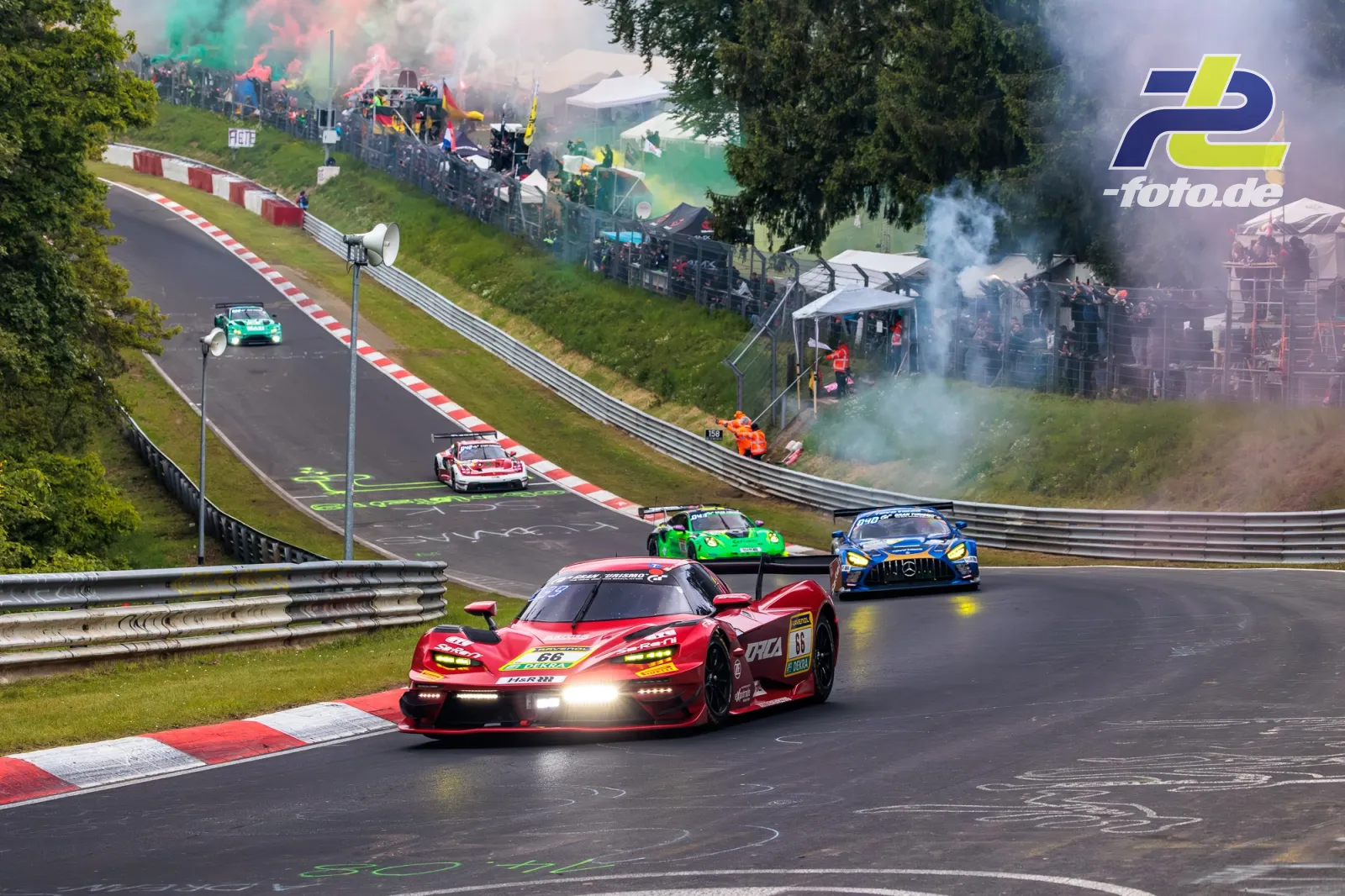 KTM X-Bow GTX #66 in Kurve während Formationsrunde zum 24h-Rennen Nürburgring, Tribüne mit Rauchschwaden im Hintergrund