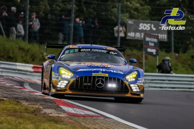 Mercedes-AMG GT3 in blau-goldener RAVENOL-Lackierung auf der Nürburgring-Nordschleife beim 24h-Rennen, Zuschauer im Hintergrund.