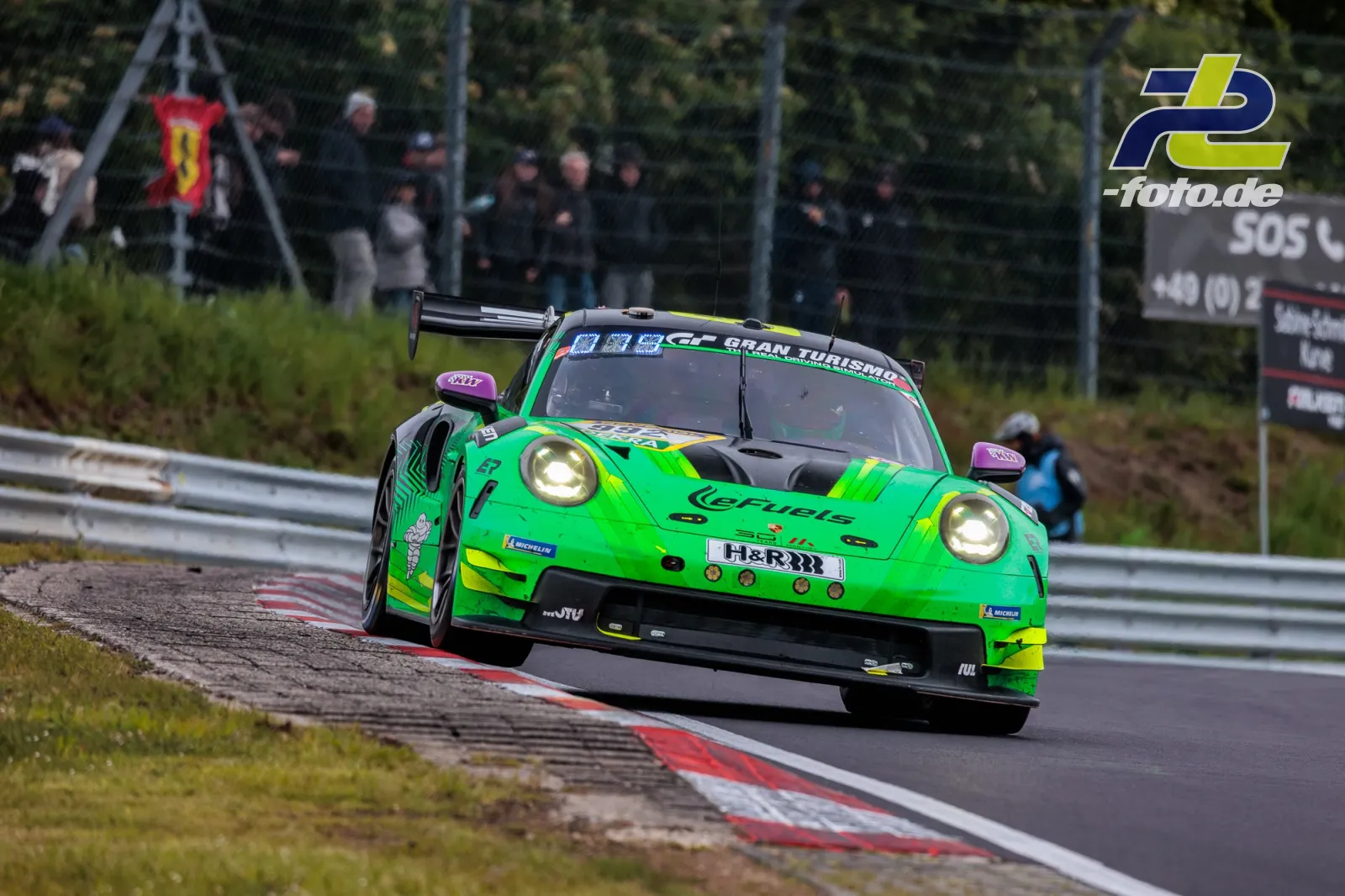 Grün-gelber Porsche 911 GT3 CUP MR in Kurve auf der Nordschleife beim 24h-Rennen Nürburgring, Zuschauer im Hintergrund.