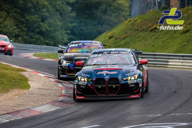 BMW M4 GT3 in grau-rot mit Startnummer 180 führt Feld auf der Nordschleife während des 24h-Rennens an, gefolgt von weiteren GT-Fahrzeugen.