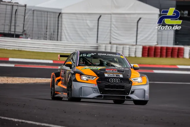 Audi TCR #821 mit orange-schwarzer Lackierung während des Qualifyings auf dem Nürburgring, fährt durch Kurve mit rot-weißen Randsteinen.