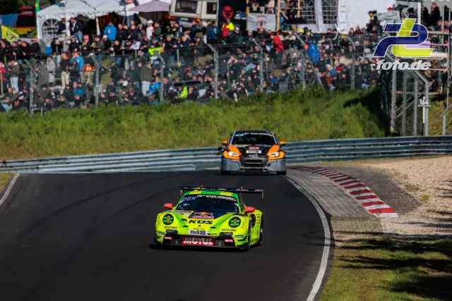 Neongelber Porsche und grau-oranger Audi auf der Nordschleife vor Zuschauertribüne während des 24h-Rennens am Nürburgring.