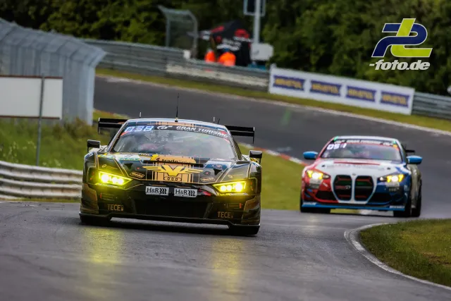Zwei GT-Rennwagen bei Nässe auf der Nordschleife während des Qualifyings zum 24h-Rennen, angeführt von einem schwarzen Audi R8 LMS