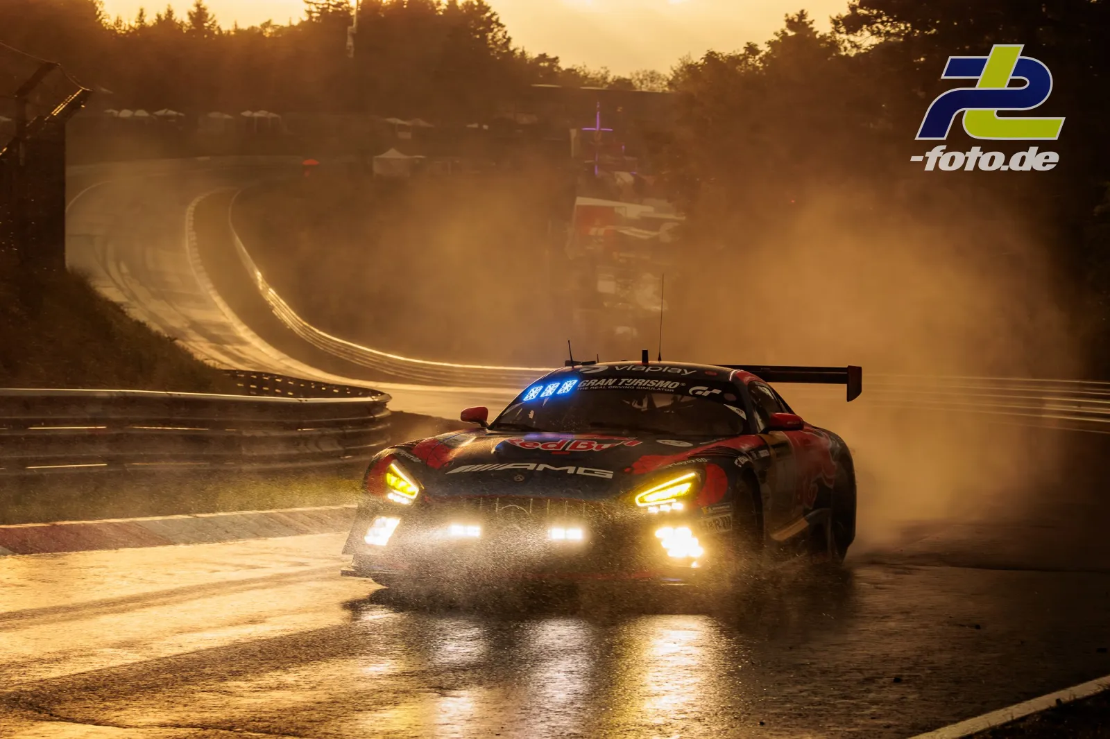 Mercedes-AMG GT3 auf nasser Nordschleife bei Sonnenuntergang mit aufgewirbeltem Sprühwasser und dramatischem Gegenlicht.