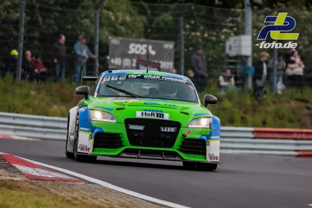 Grün-blauer Audi TT RS in einer Kurve auf dem Nürburgring beim 24-Stunden-Rennen, Zuschauer im Hintergrund.