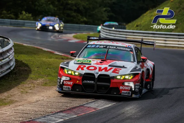BMW M4 GT3 mit ROWE-Lackierung auf der Nürburgring-Nordschleife beim 24-Stunden-Rennen, verfolgt von zwei weiteren GT-Fahrzeugen.