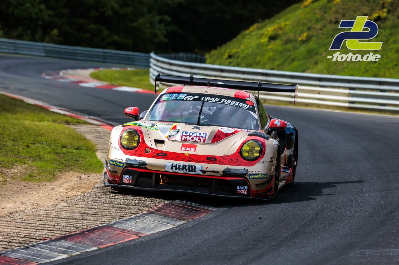 Porsche 911 GT3 R in Kurve auf der Nürburgring-Nordschleife beim 24h-Rennen, weiß-rote Lackierung mit Heckflügel.