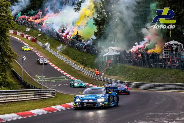 Mehrere GT3-Fahrzeuge passieren bei der Formationsrunde Brünnchen, Zuschauer zünden bunten Rauch in der Breidscheid-Tribüne