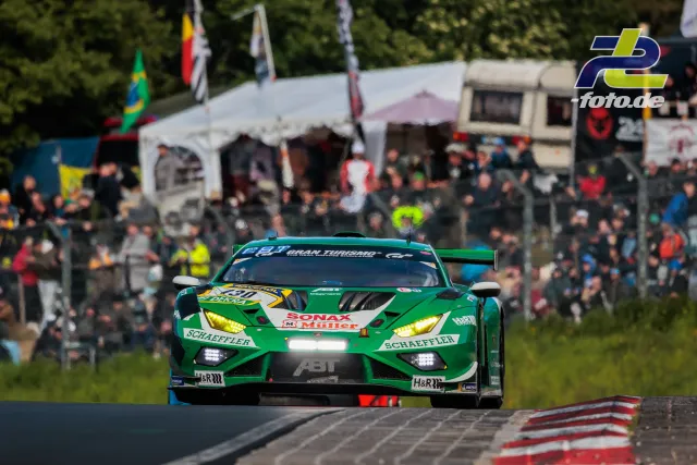 Grüner GT-Rennwagen mit gelben Scheinwerfern auf der Nordschleife vor Zuschauern beim 24h-Rennen Nürburgring