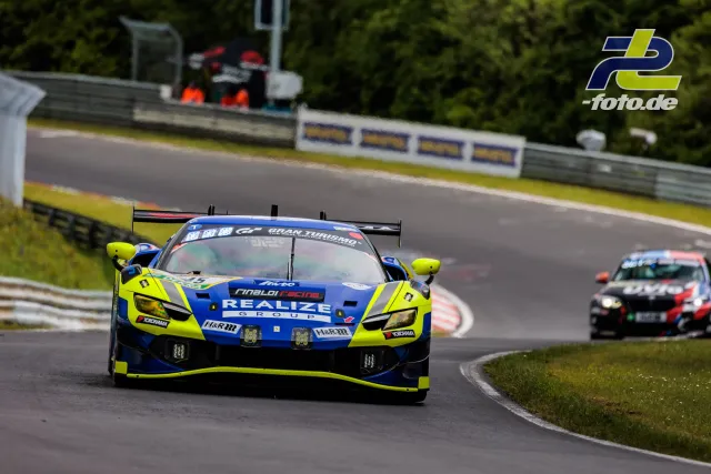 Ferrari in neongelb-blauer Lackierung in Kurve auf der Nordschleife, gefolgt von einem weiteren Rennwagen während des 24h-Rennens am Nürburgring.