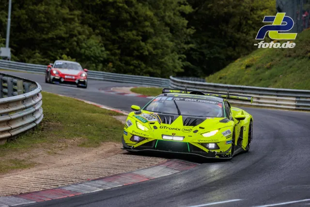 Neongelber Lamborghini in Kurve auf der Nordschleife, Porsche folgt im Hintergrund während des 24h-Rennens
