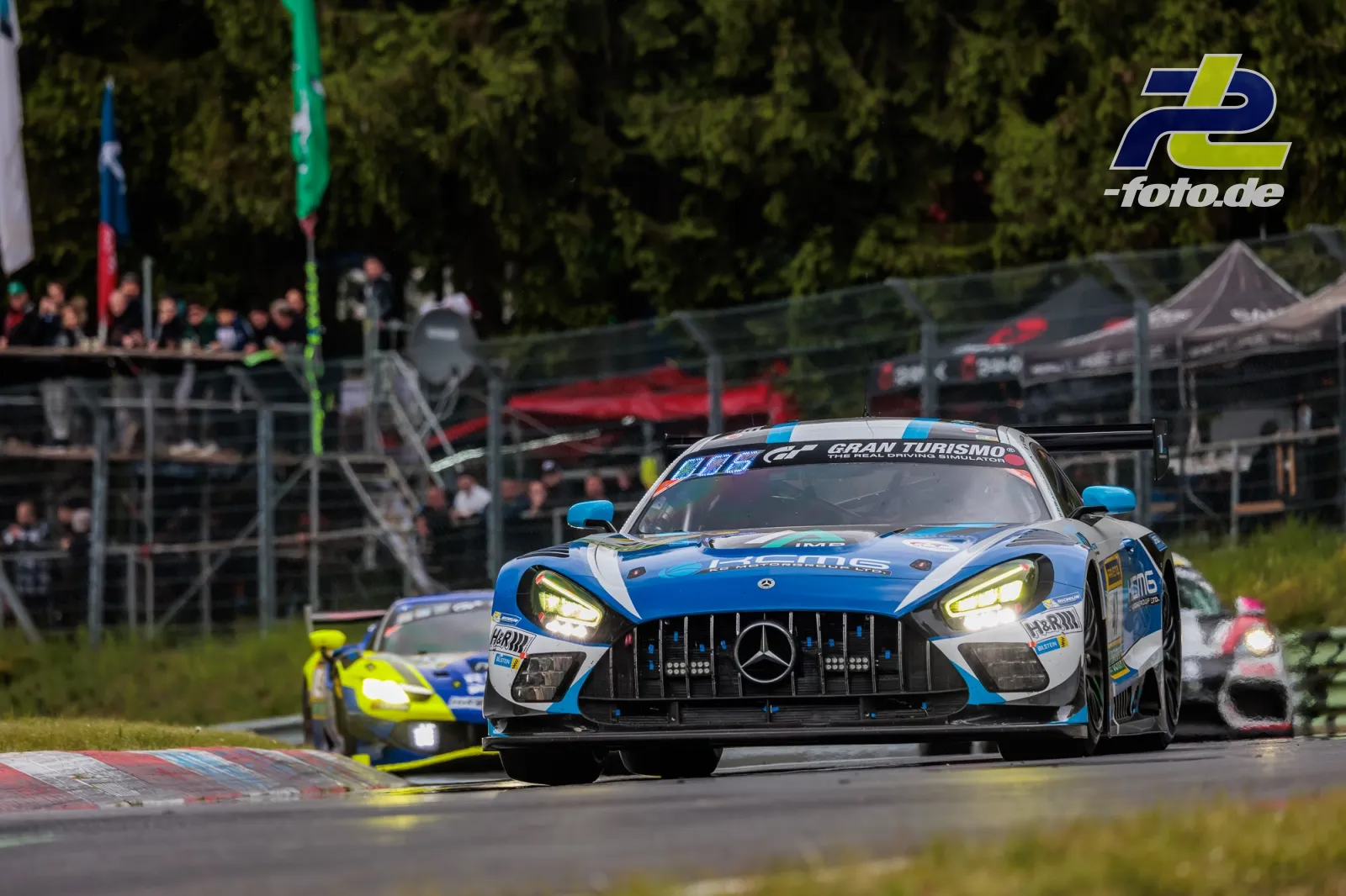 Mercedes-AMG GT3 #47 von KCMG in blau-weißer Lackierung während des 24h-Rennens am Nürburgring vor Tribüne.