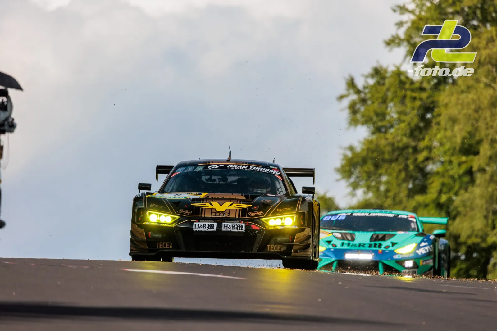 Audi R8 LMS GT3 evo II #8 vor türkisem Konkurrenten über Kuppe beim 24h Nürburgring 2026, beide mit eingeschalteten Scheinwerfern