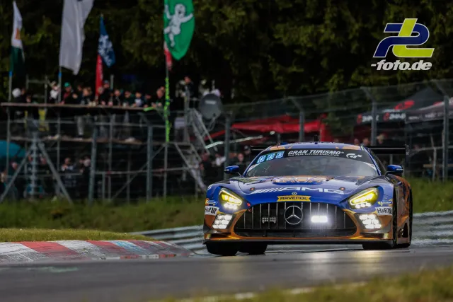 Mercedes-AMG GT3 in der Nordschleife während des 24-Stunden-Rennens, Zuschauertribünen im Hintergrund.