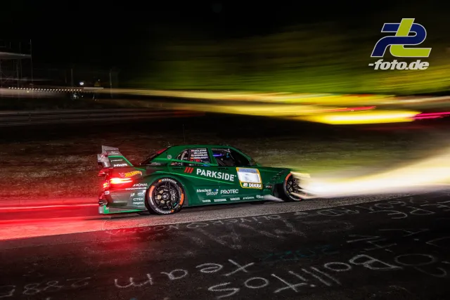 Grüner Rennwagen mit PARKSIDE-Sponsoring im Nachtrennen bei 24h Nürburgring, Mitzieher mit Lichtschweif eines überholenden Fahrzeugs.